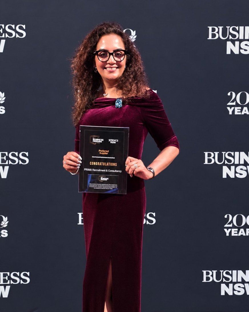 Priya Menon Gillett, Founder and Managing Director of PRIMA Recruitment & Consultancy, holding the Regional Finalist certificate in front of the Business NSW media wall at the 2026 Sydney Business Awards, Sydney Town Hall